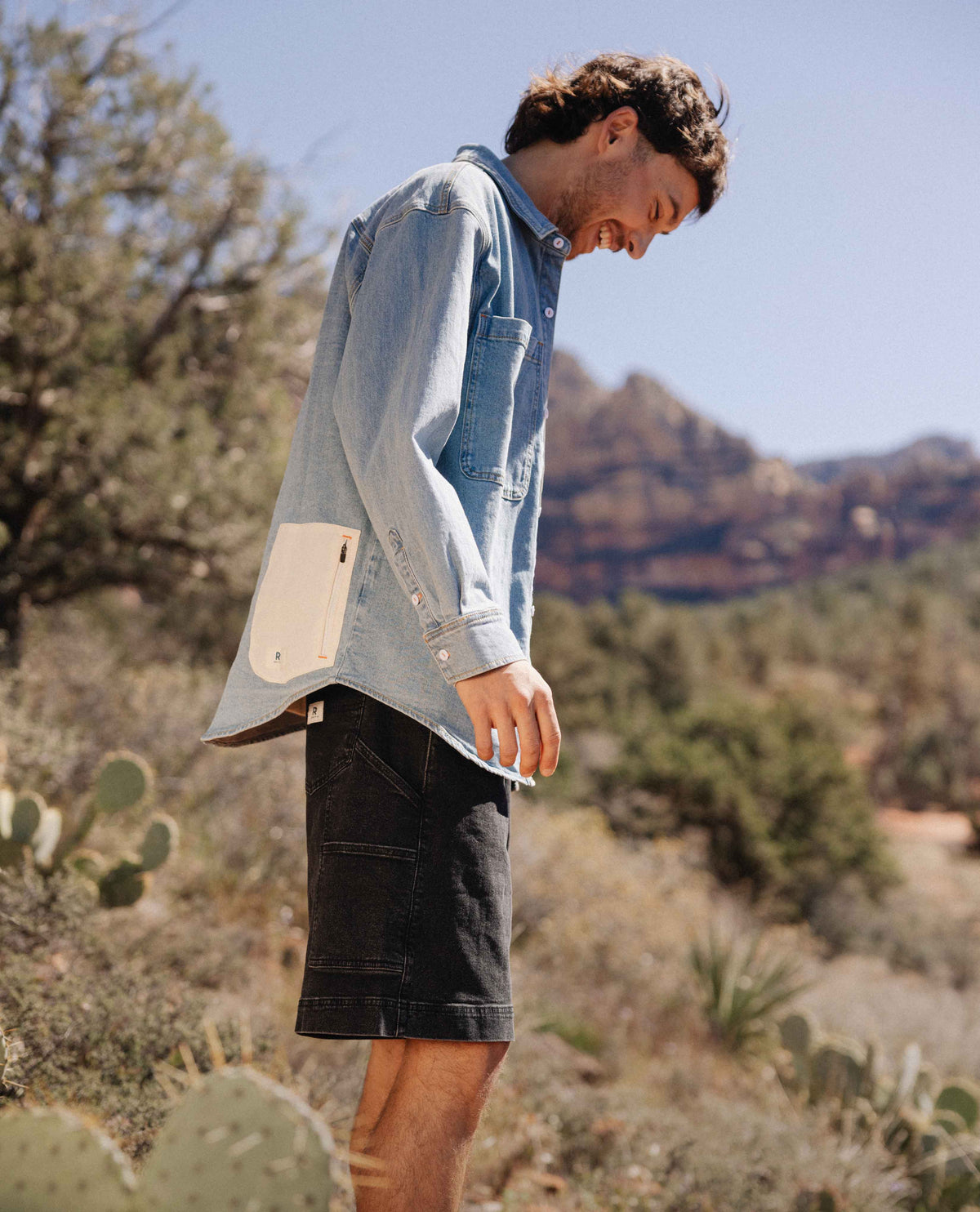 Person wearing a light blue denim shirt with beige patch in a desert setting