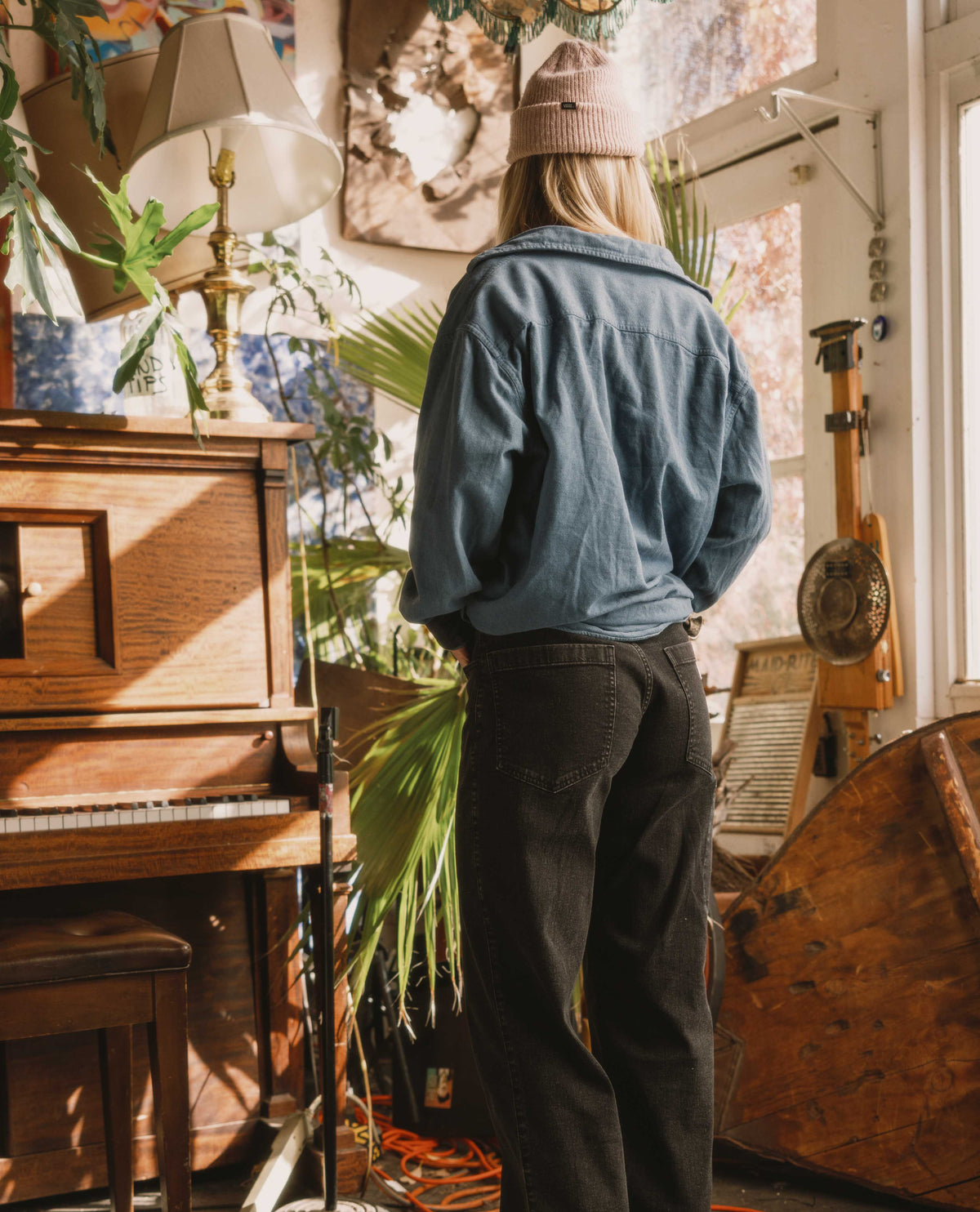 Person standing in a room with plants and musical instruments