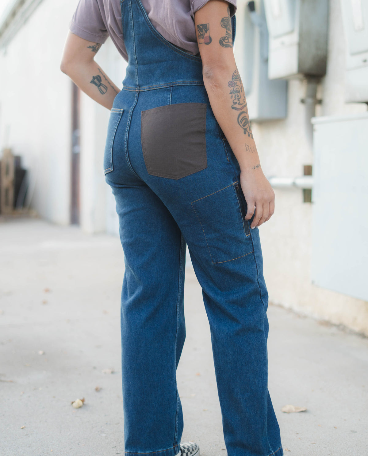 Person wearing blue denim overalls with a plain background