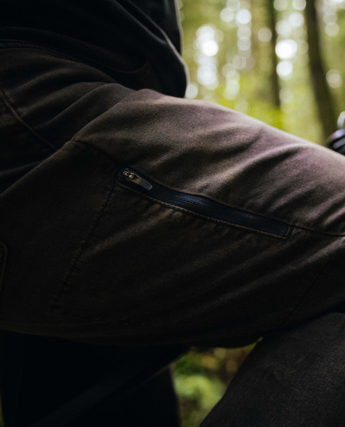 Close-up of a person wearing a dark jacket with a blurred forest background