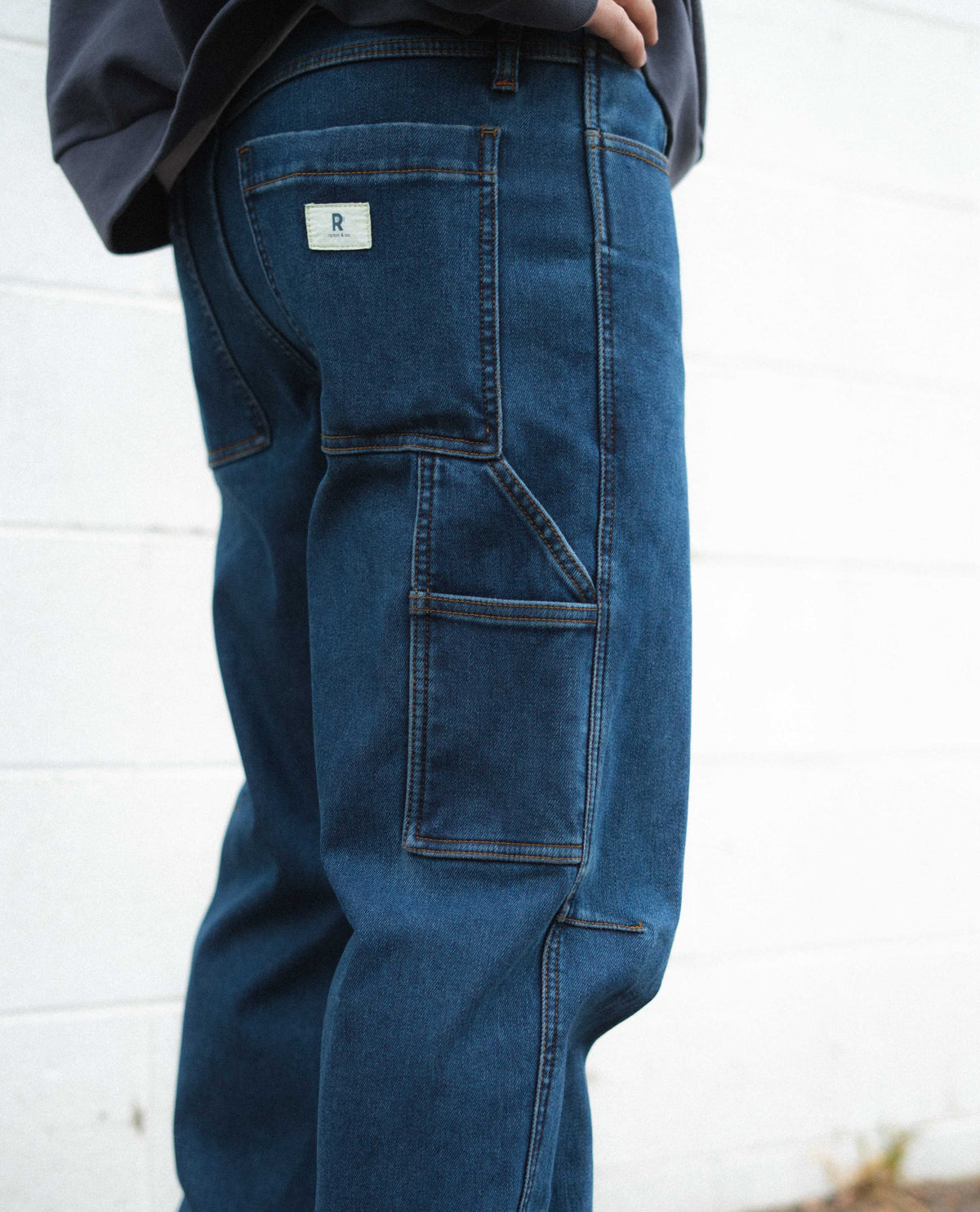 Blue jeans with a brand logo on the back pocket against a white background