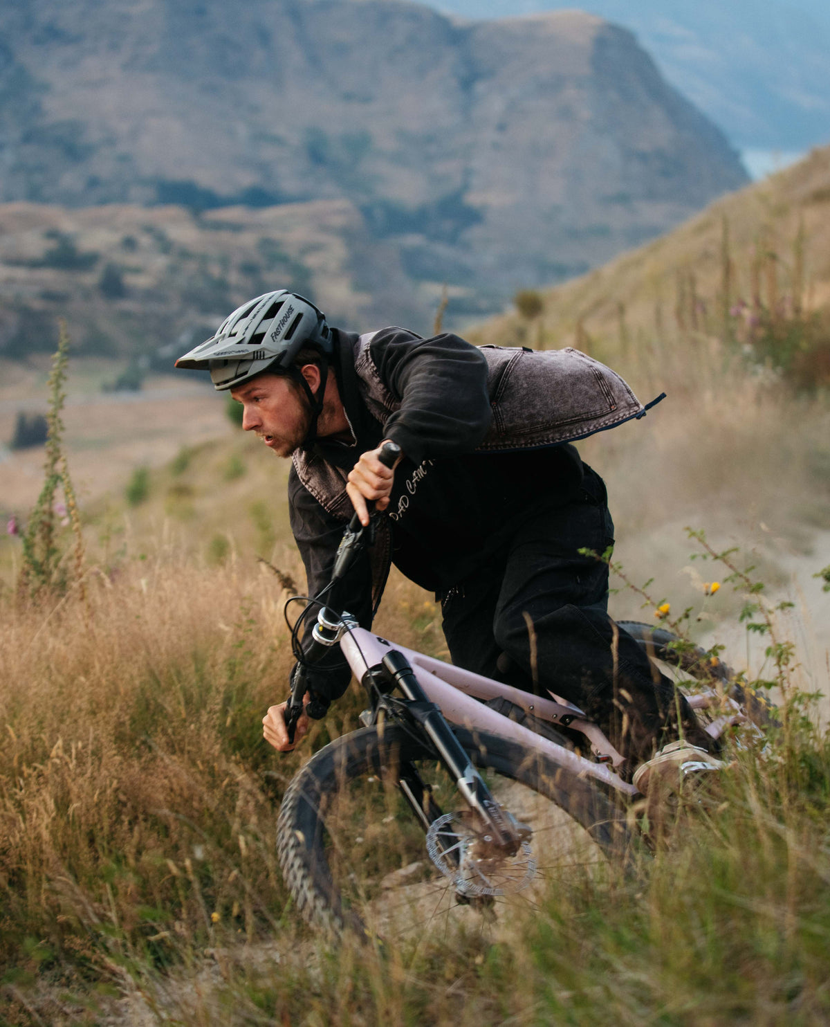 Man riding a mountain bike on a trail with mountains in the background