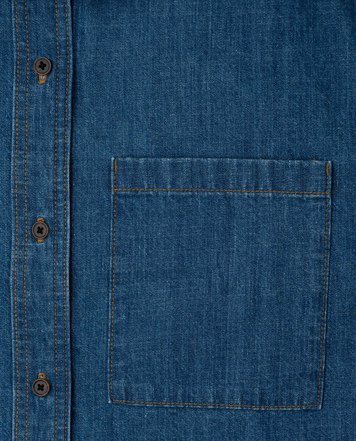 Close-up of a blue denim shirt with a pocket and buttons.