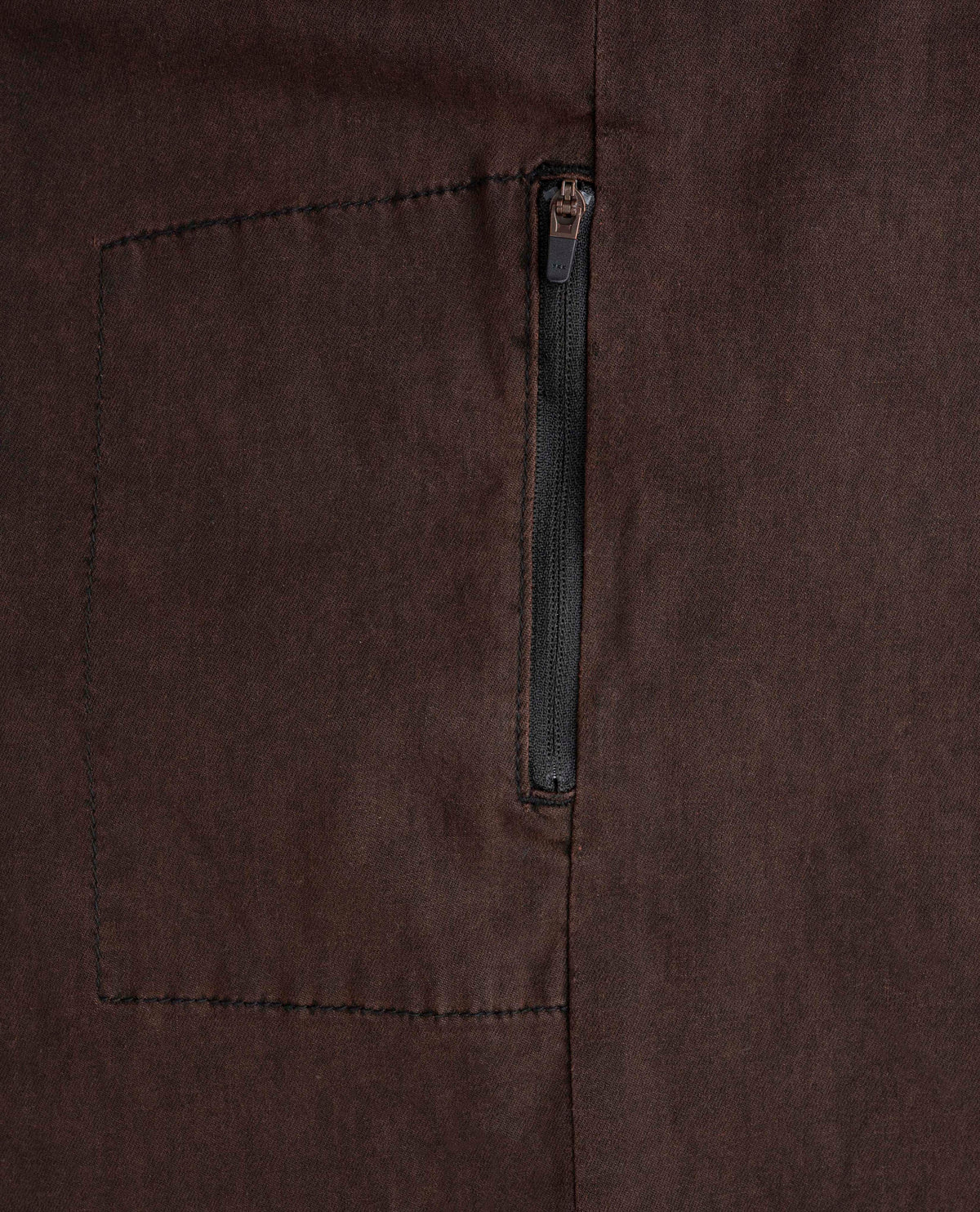 Close-up of a brown fabric pocket with a zipper on a matching brown background