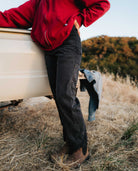 Girl wearing black utility pants with red top next to a pickup truck