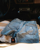 Light blue denim shorts placed on a blanket inside an old truck.