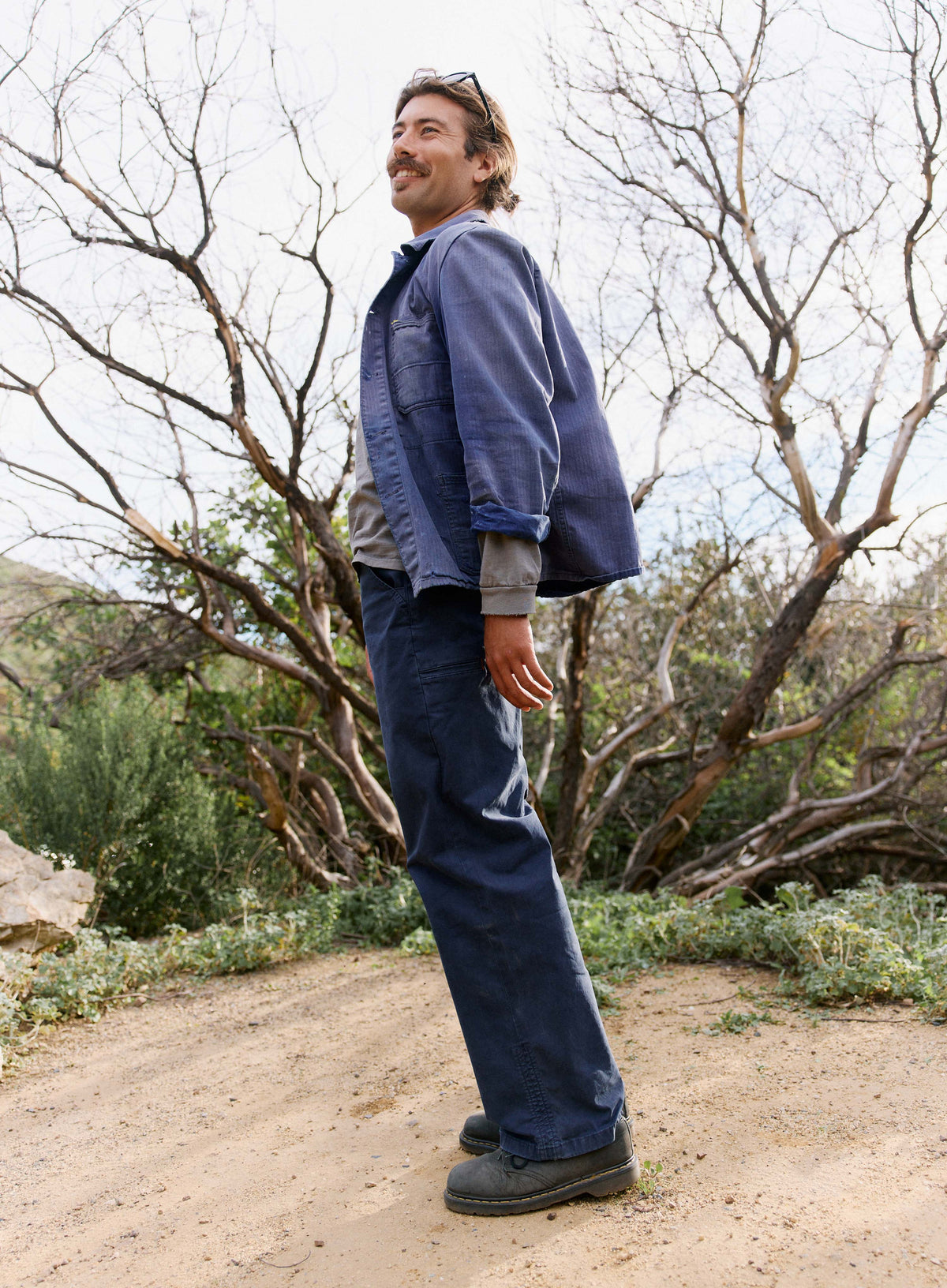Man standing outdoors in a natural setting wearing a blue jacket and pants.