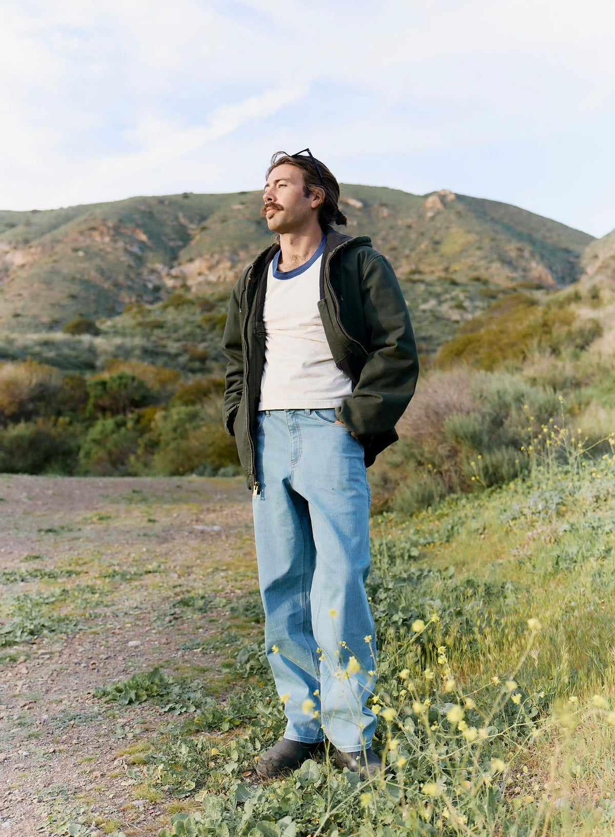 Man standing in a desert landscape with mountains in the background