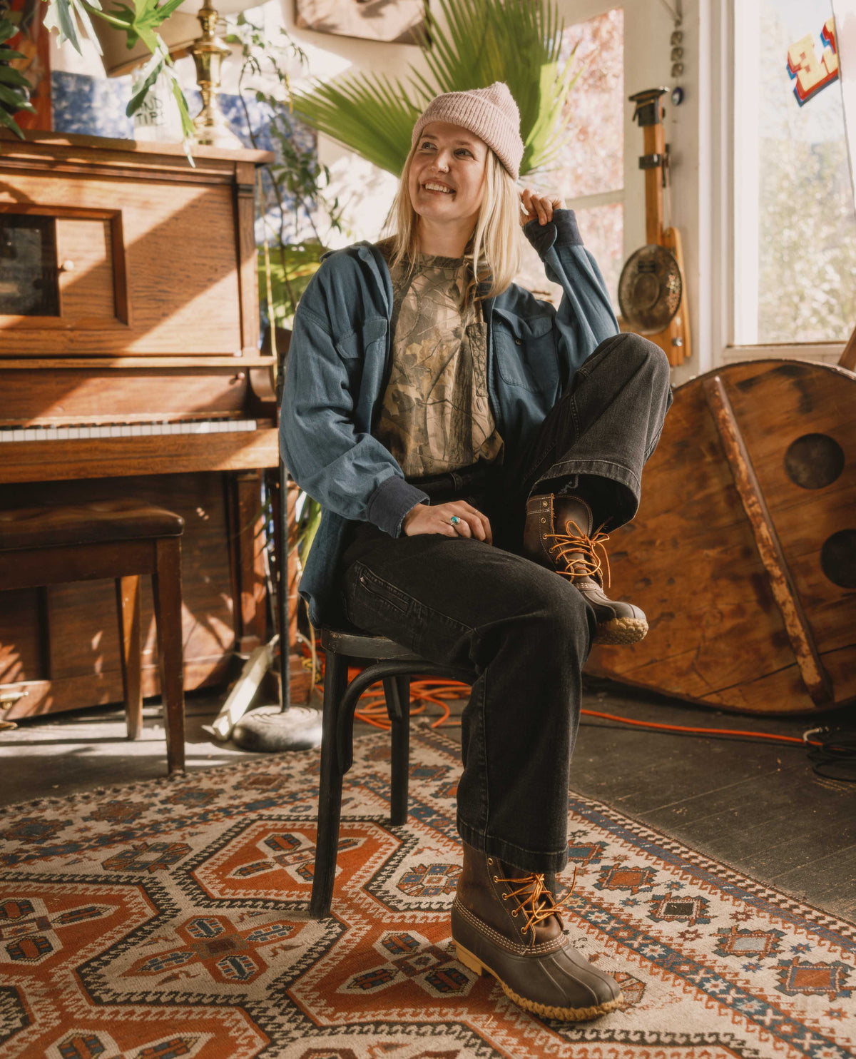 Person sitting on a chair in a room with a piano and decorative rug