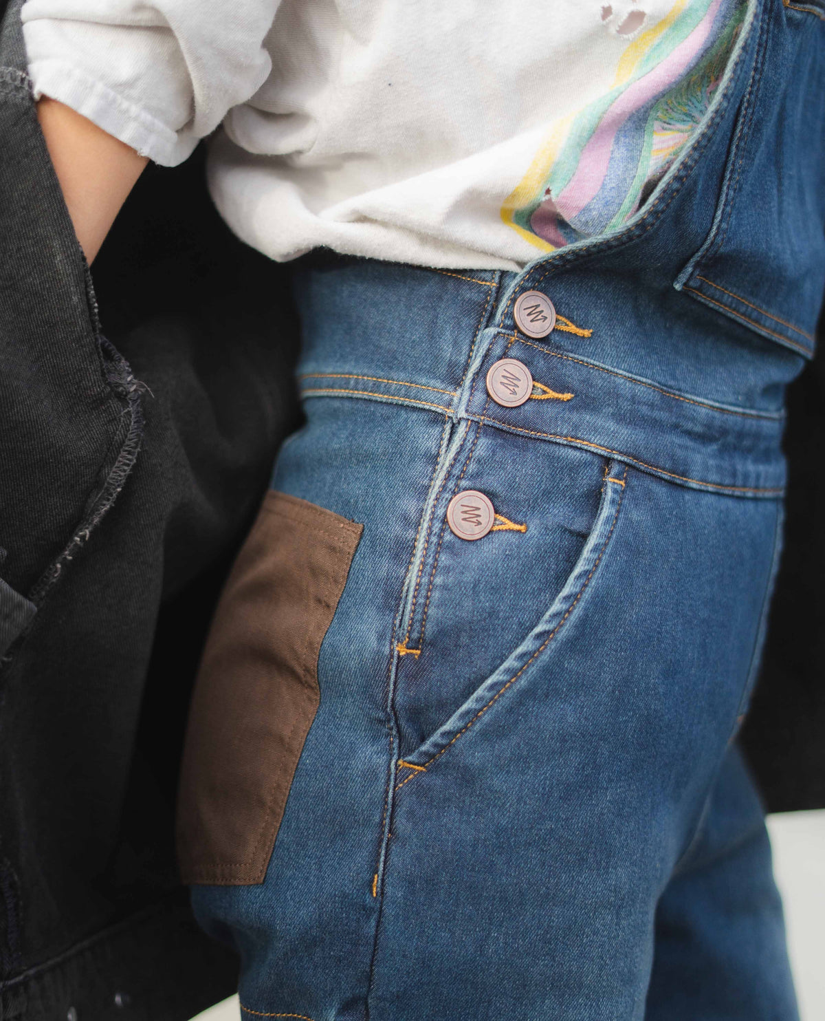 Close-up of a person wearing a blue denim jacket with brown patches.