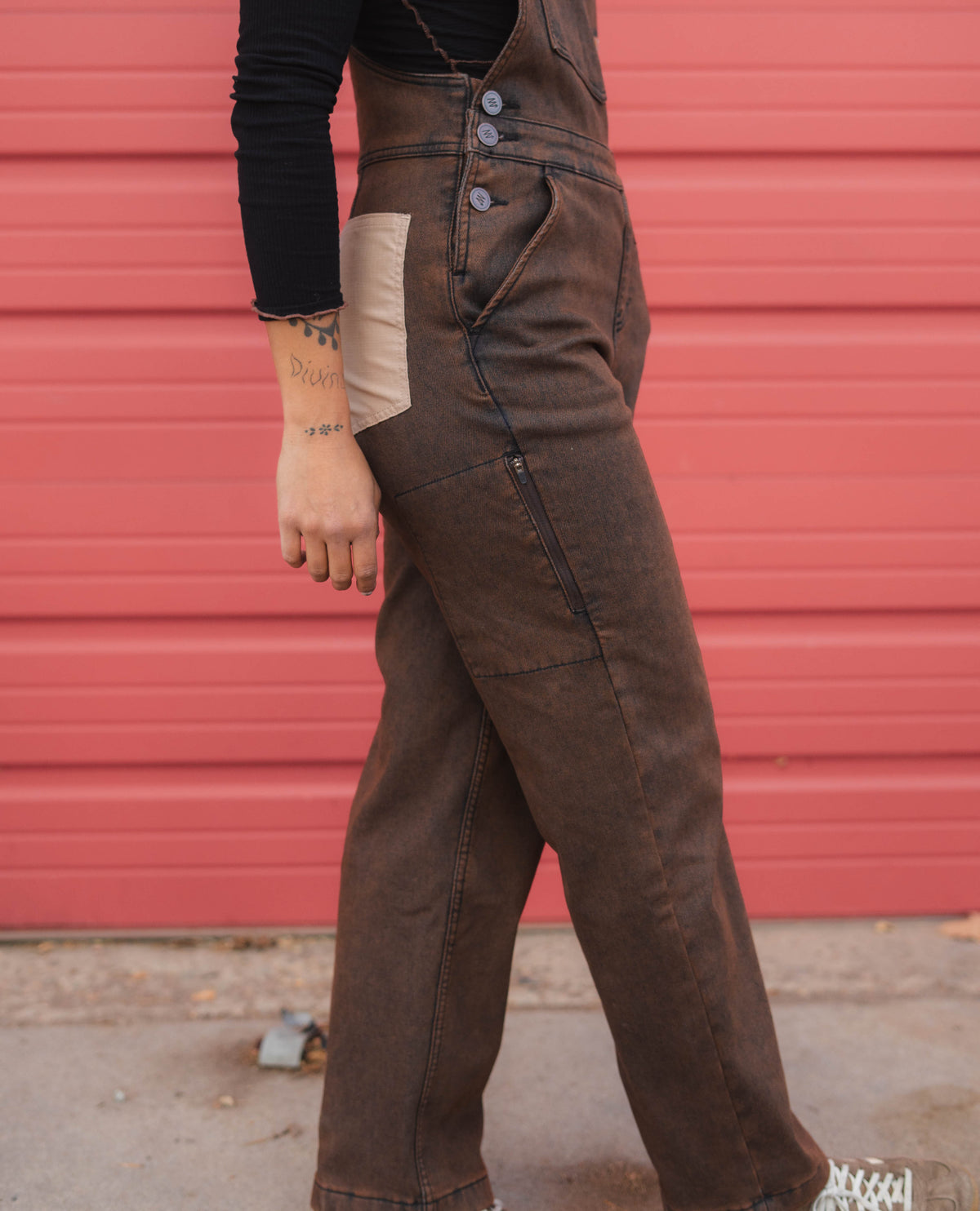 Person wearing brown overalls against a red background