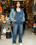 Person wearing blue denim overalls in a workshop setting