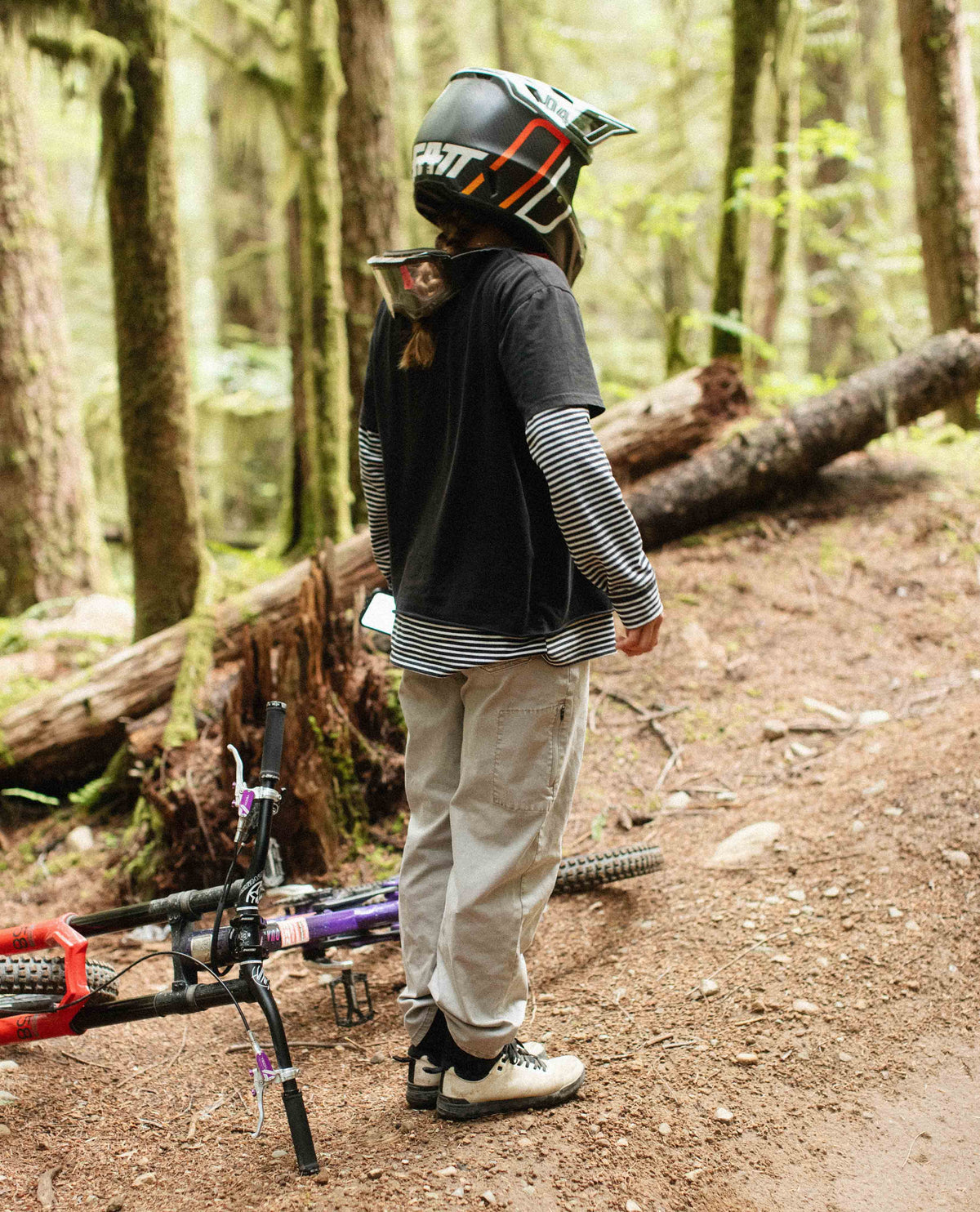 Janelle with a mountain bike in a forest setting wearing a helmet.