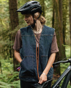 Person wearing a helmet and denim vest in a forest setting