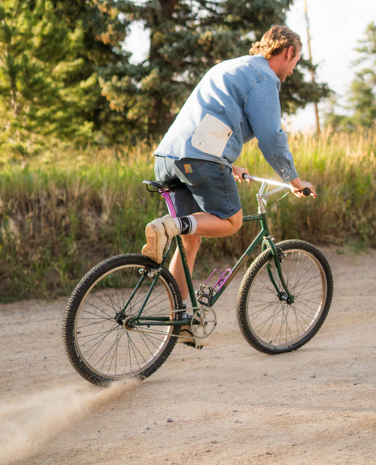 Person riding a bicycle on a dirt path with trees in the background