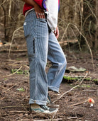 Person wearing blue corduroy pants walking through a forest