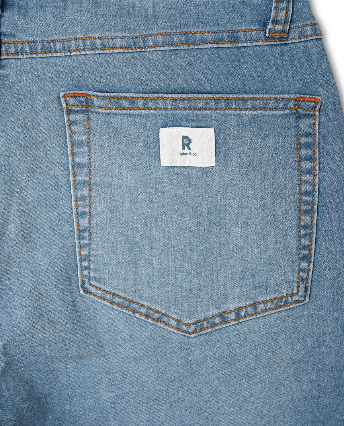 Close-up of a blue denim pocket with a brand label on a white background