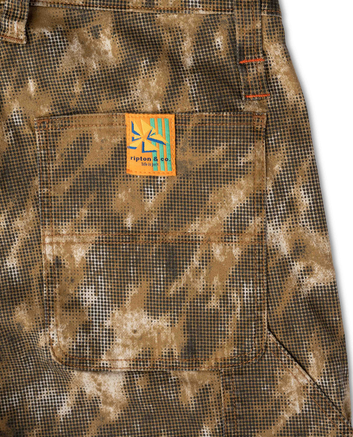 Close-up of a camouflage-patterned fabric with a visible brand logo on a white background