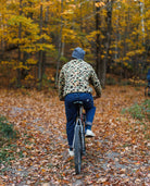Person riding a bicycle through a forest with autumn foliage