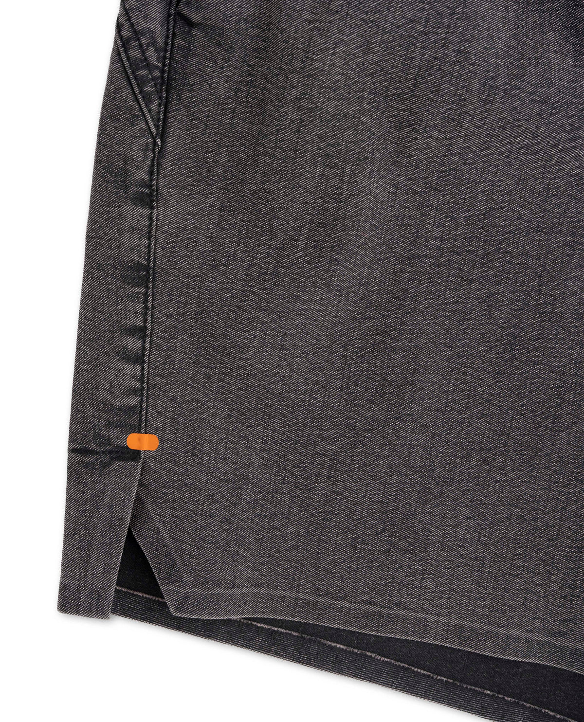 Close-up of a dark gray fabric with an orange tag on a white background