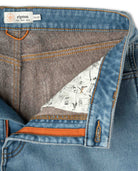 Close-up of a blue denim fabric with a patterned lining and orange stitching, featuring the Ripton brand label.