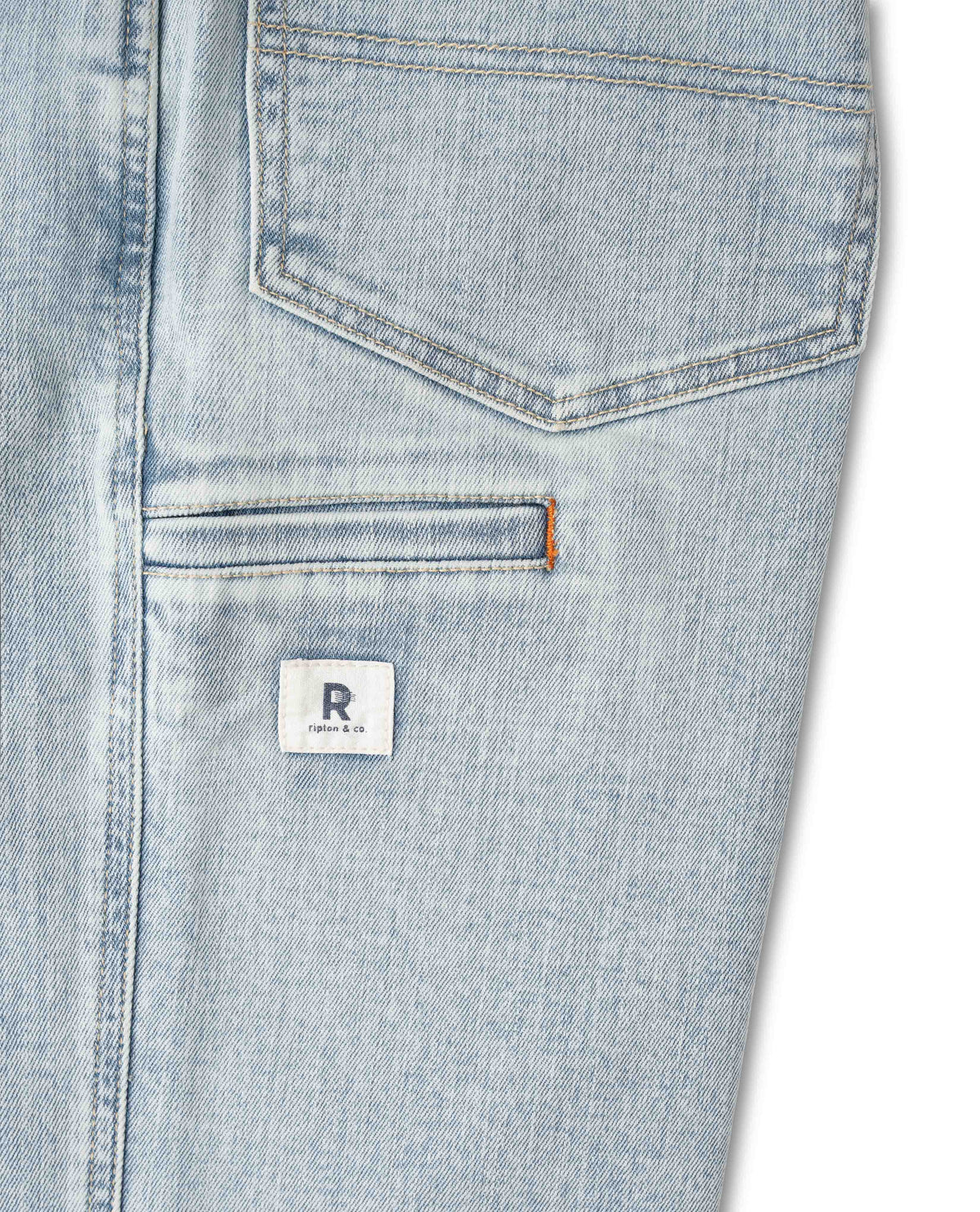 Close-up of a light blue denim pocket with a brand logo on a white background