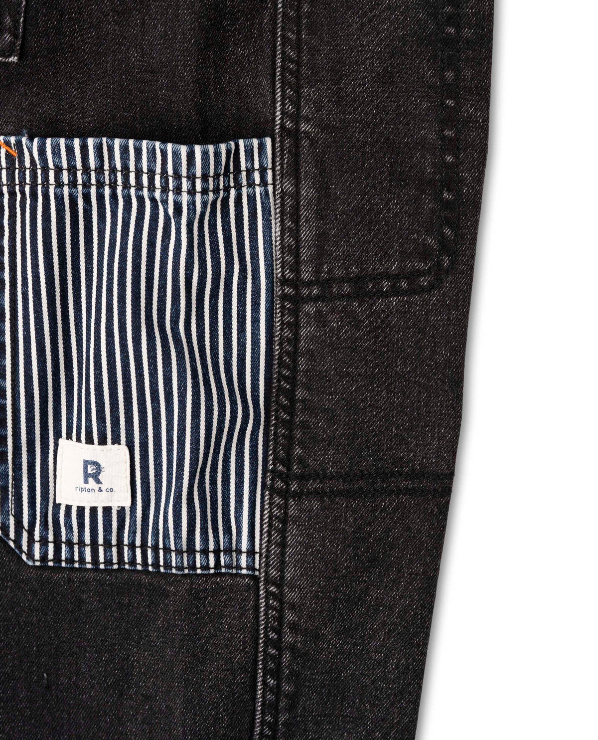 Close-up of a black denim jacket with a striped pocket and a visible brand logo on a white background.