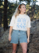 Blonde woman standing outside wearing blue shorts and white shirt 