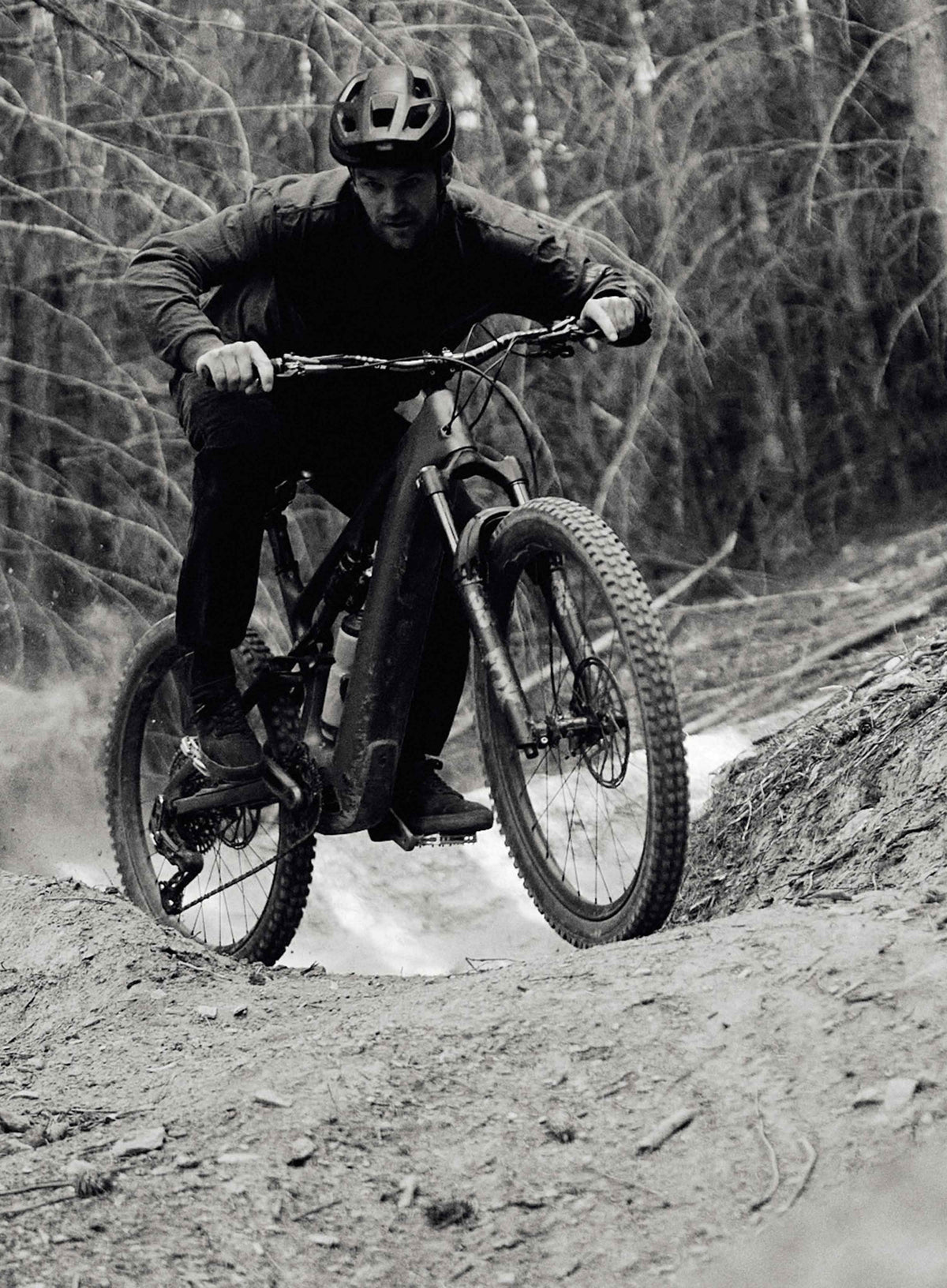 Person riding a mountain bike on a trail with trees in the background