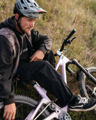 Man sitting on a bicycle in a grassy outdoor setting