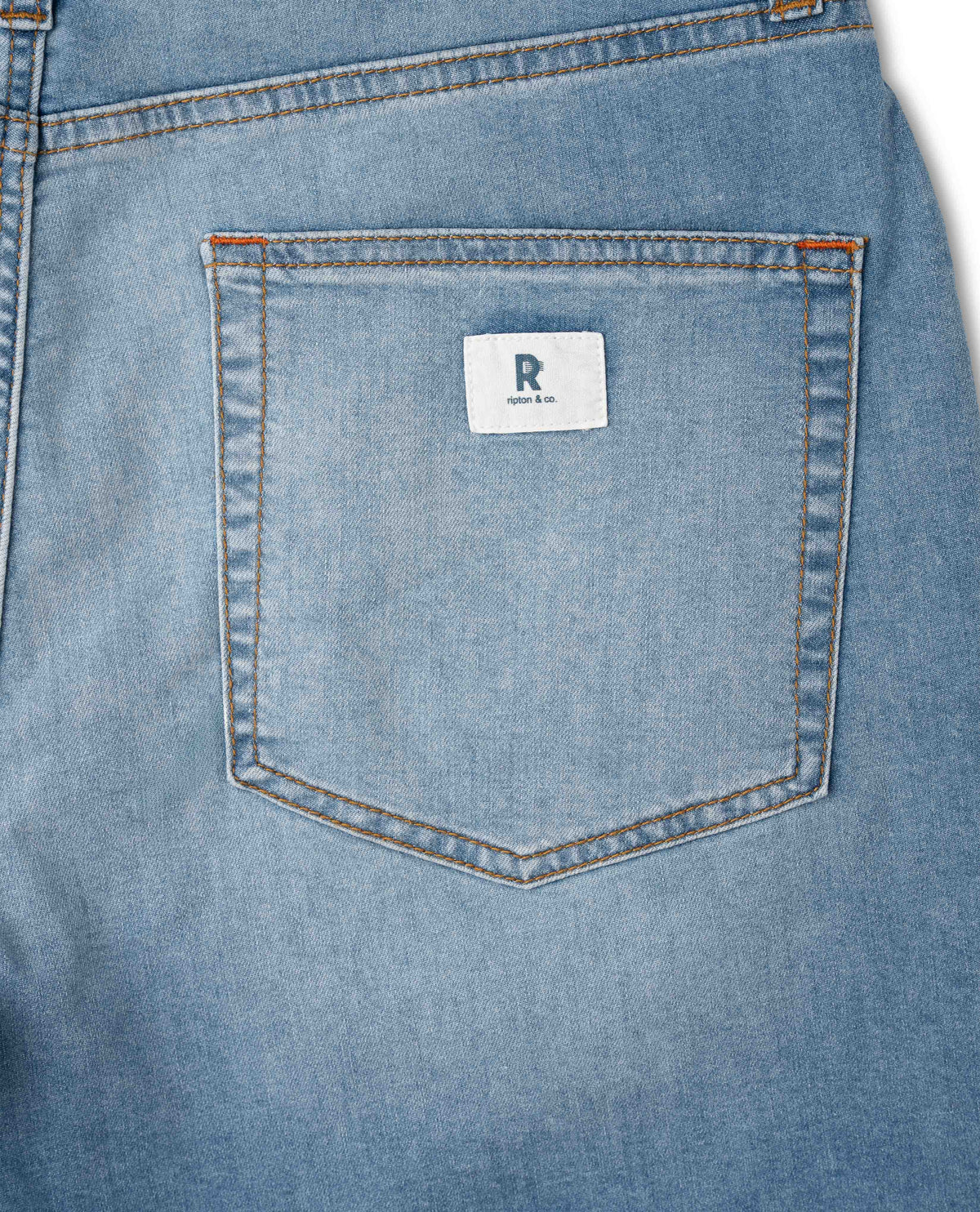 Close-up of a blue denim pocket with a brand label on a white background