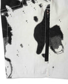Close-up of a white jacket with black abstract patterns and a zipper.