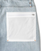 Close-up of a light blue denim pocket with a white patch on a white background
