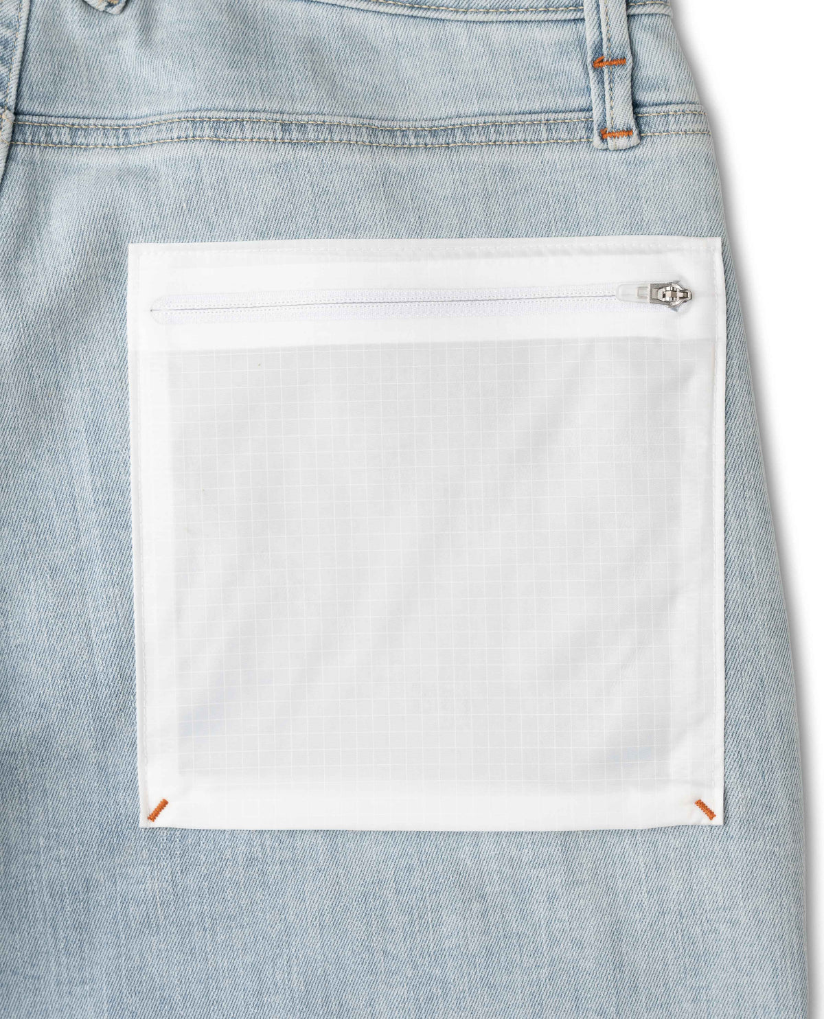 Close-up of a light blue denim pocket with a white patch on a white background