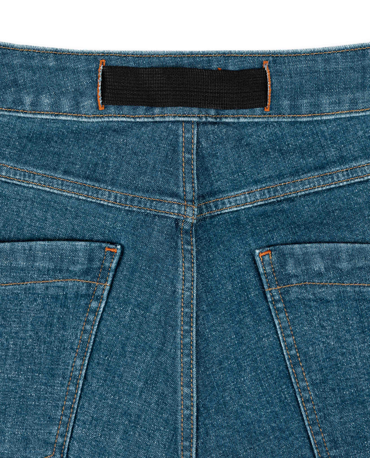 Close-up of blue denim jeans with a black label on a white background