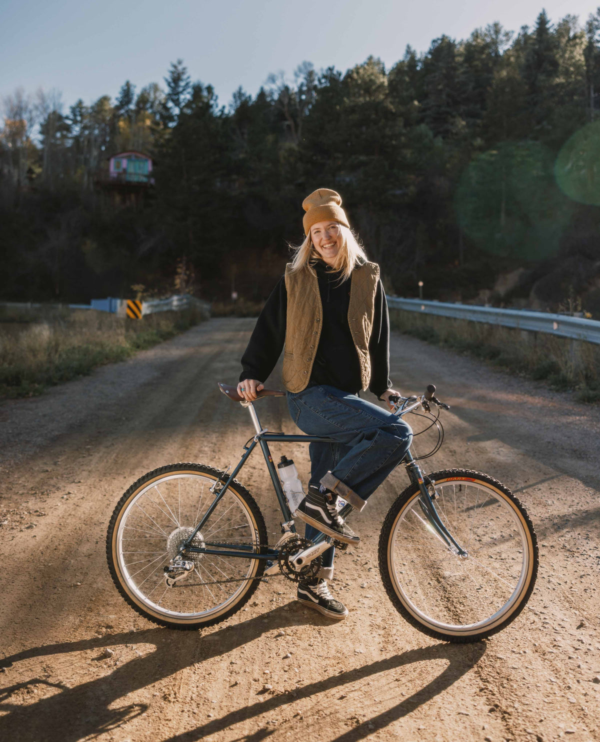 Person riding a bicycle on a dirt road with trees in the background