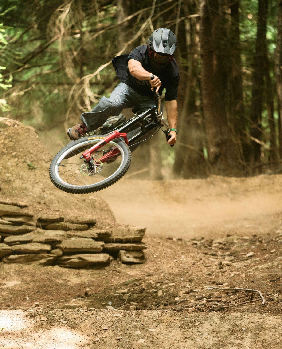 Person riding a mountain bike on a dirt trail with trees in the background
