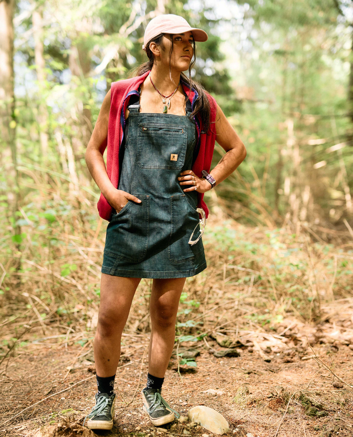 Woman in a denim dress and cap hiking in a forest