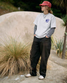 Person wearing a red cap and white sweatshirt with black and white striped sleeves, standing outdoors.